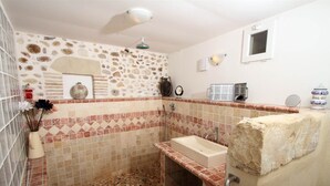 Un baño con paredes de mosaicos, un lavabo y una ducha.