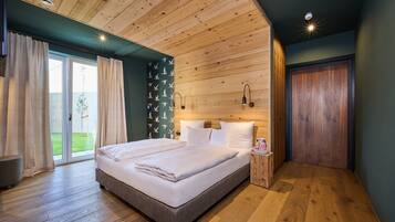 Un dormitorio moderno con techo de madera, una cama grande, una mesita de noche y un ventanal corredero a un balcón.