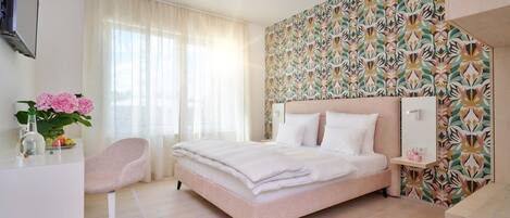 A modern bedroom with a large bed, a desk, and a chair.