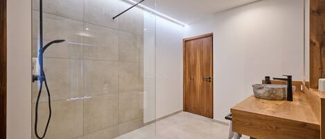 A modern bathroom with a glass-enclosed shower, a wooden vanity, and a large mirror.