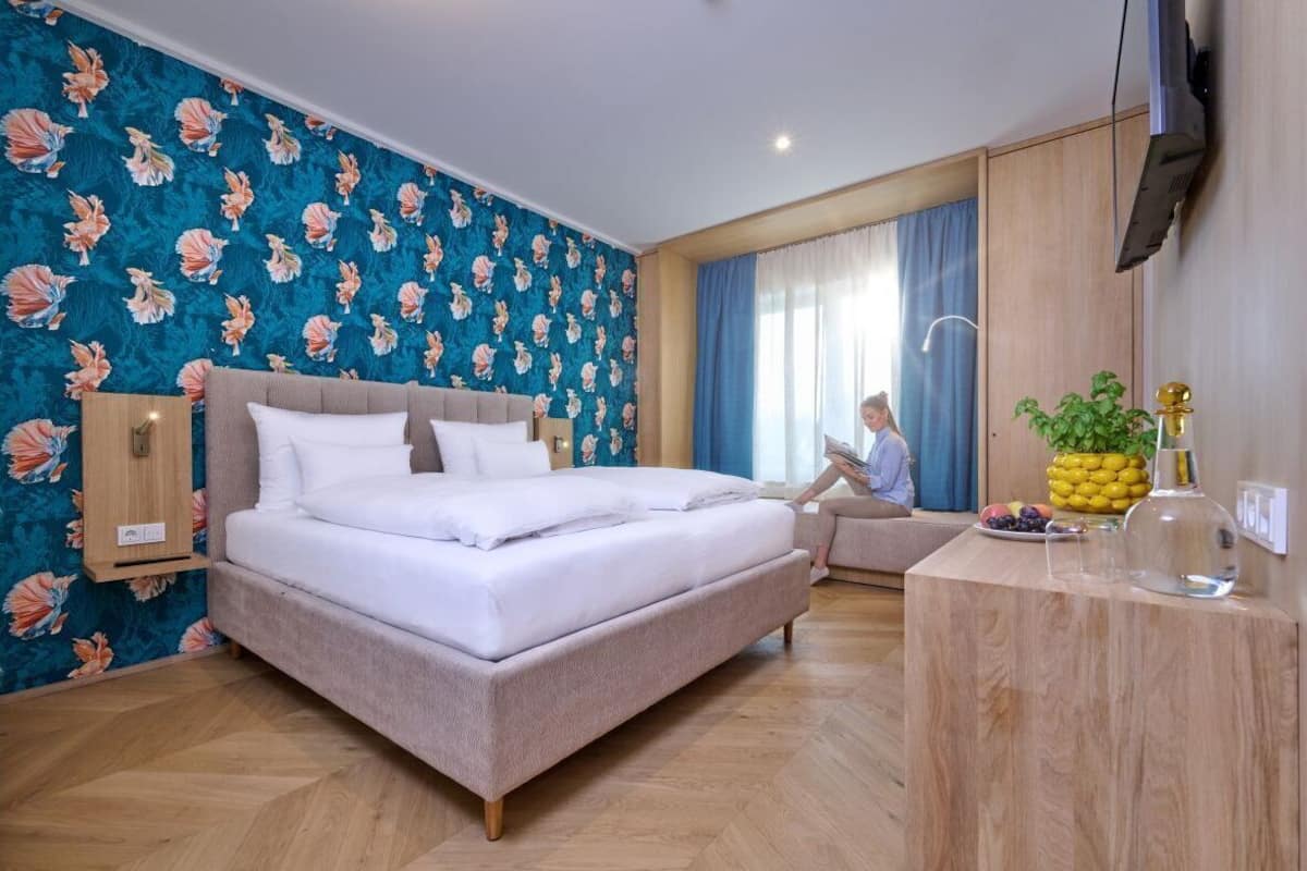 A hotel room with a bed, a desk, a television, and a window with curtains.