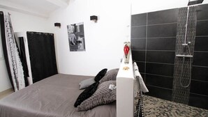 Une chambre à coucher comprenant un lit, une douche et un luminaire fixé au mur.