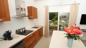 Une cuisine avec des meubles de rangement en bois, une cuisinière encastrée, un évier et un coin repas comprenant une table et des chaises.