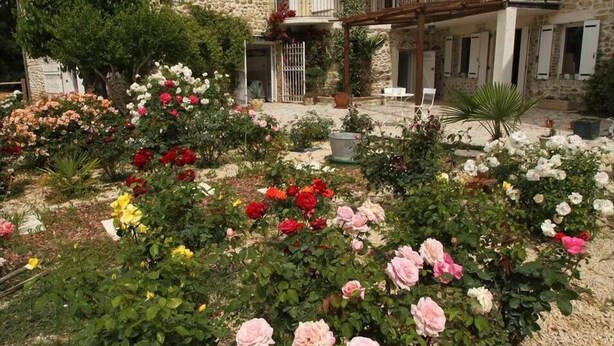 Un bâtiment en pierre avec un jardin devant.