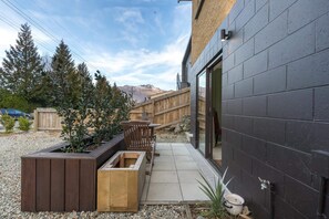 Ein modernes Gebäude mit dunkler Fassade, einer Holzterrasse und einer Schotterpatio.