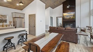 A modern kitchen with a built-in refrigerator, wooden bar stools, and a dining table. - "The Ridgeline" Modern Dog-Friendly Cabin Near PF & Gatlinburg (Sevierville)