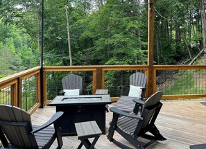 A deck with Adirondack chairs, a fire pit, and a view of a forest. - "The Ridgeline" Modern Dog-Friendly Cabin Near PF & Gatlinburg (Sevierville)