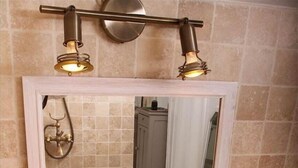Een badkamer met een beige wastafel, een spiegel en twee wandlampen.