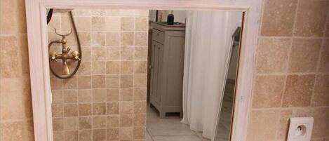 Une salle de bain avec un lavabo beige, un miroir et deux appliques murales.