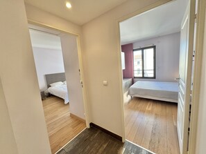 Ein Schlafzimmer mit einem Bett, einem Fenster und einer Tür zu einem anderen Raum.