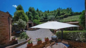 An outdoor patio area with a table and chairs, surrounded by brick walls and potted plants. - PYRUS - First floor apartment 75 m2 (Montaione)