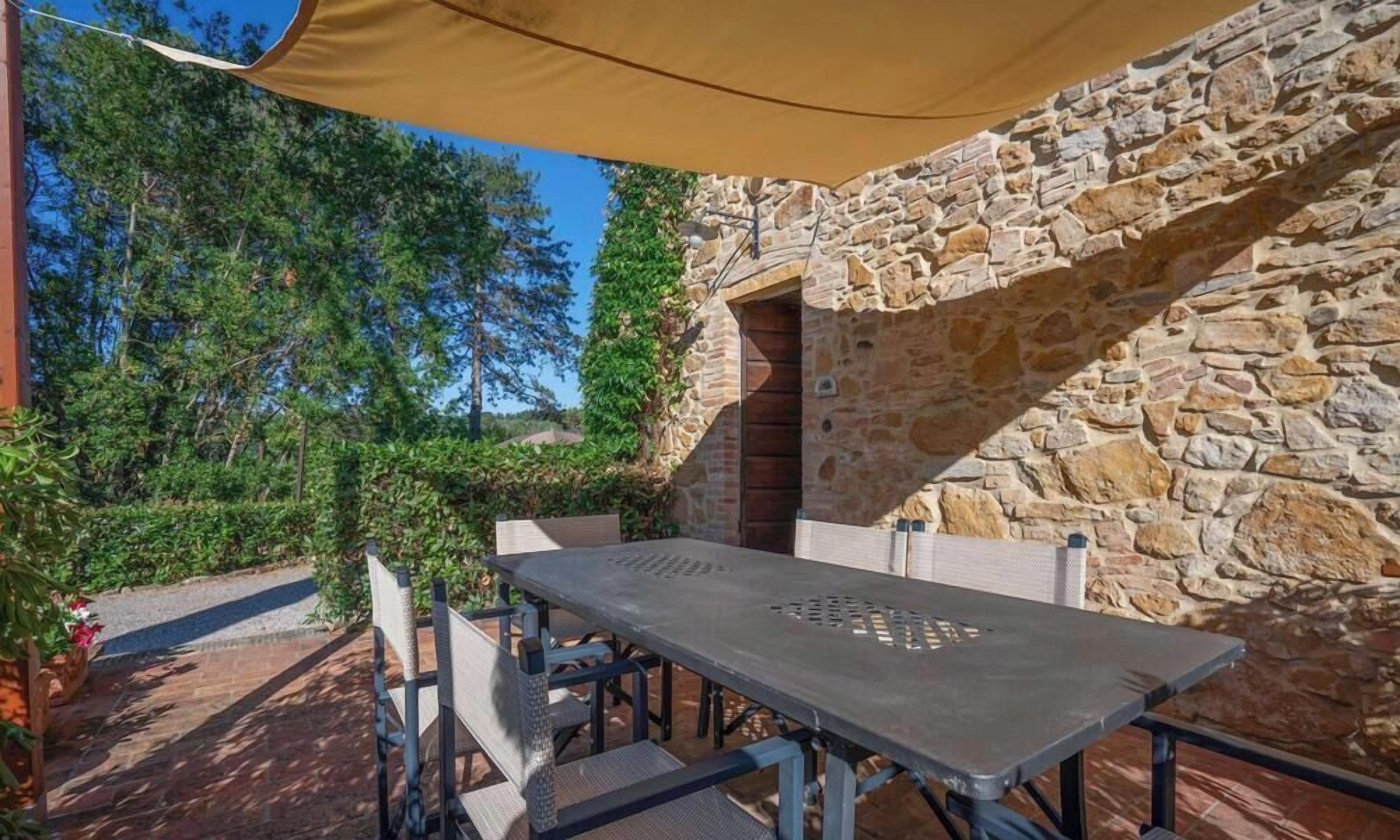 An outdoor patio with a stone wall, a table, and chairs.