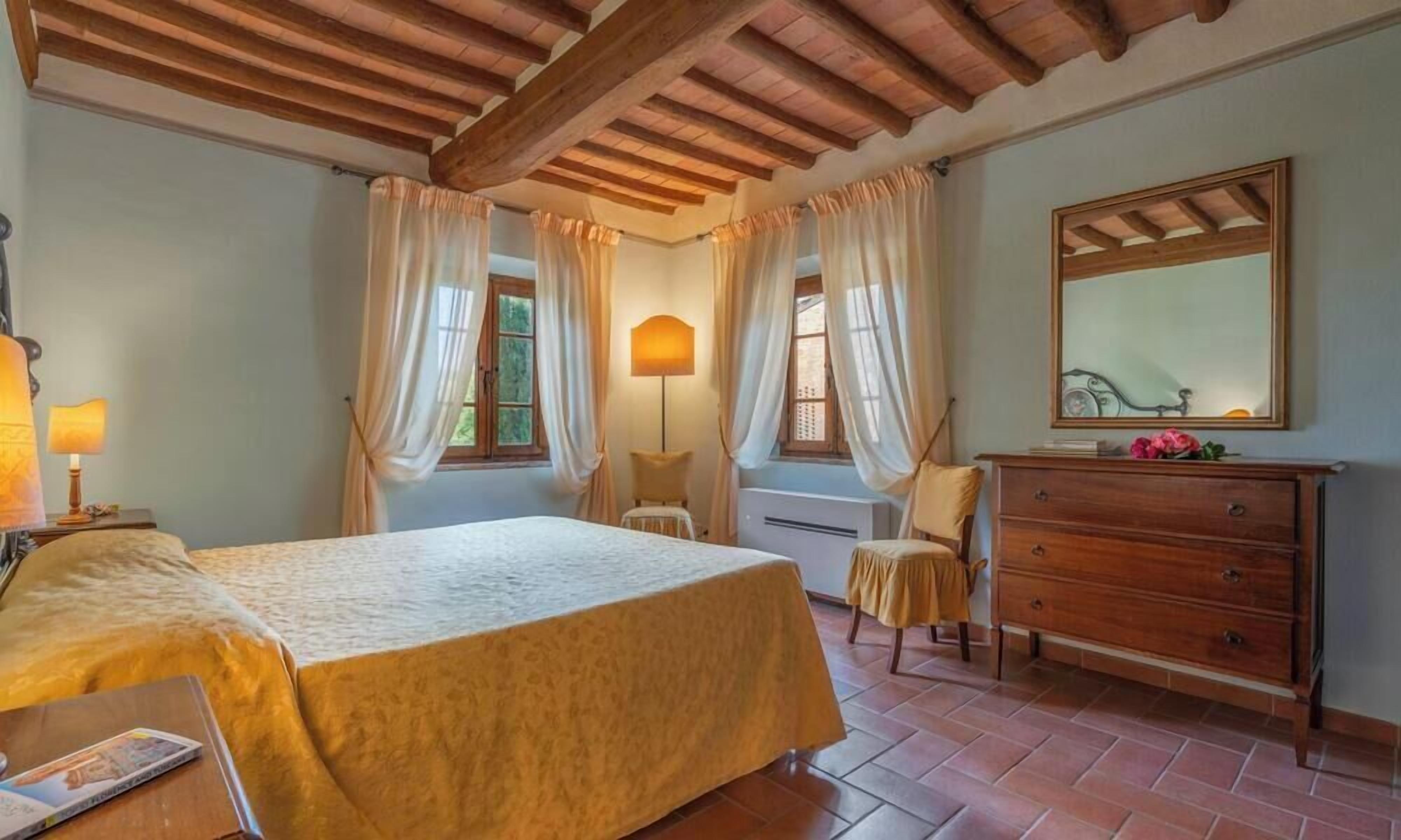 A bedroom with a bed, a dresser, a chair, and a lamp.