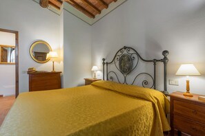 Une chambre à coucher comprenant un lit, une table de chevet, une commode, un miroir et une lampe fixée au mur.
