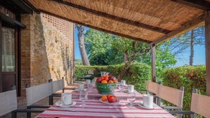 An outdoor dining area with a table set for two, surrounded by stone walls and a thatched roof. - ARMENIACA - Two-storey apartment measuring 120 m2 (Montaione)