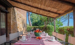 An outdoor dining area with a table set for two, surrounded by stone walls and a thatched roof. - ARMENIACA - Two-storey apartment measuring 120 m2 (Montaione)