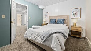 A bedroom with a bed, nightstands, a lamp, and framed floral artwork.