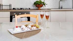 A kitchen with a dining table set for two, featuring a tray of pastries and two glasses of tea. - Maridda sicilian vacation home (Giarre)
