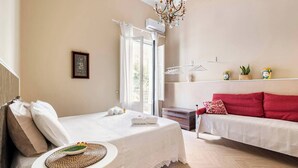 A hotel room with a bed, a red sofa, a small table with a bowl, and a window with curtains. - Maridda sicilian vacation home (Giarre)