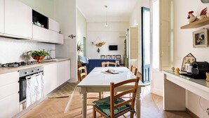 A modern kitchen with a dining area, wooden chairs, a table, and a TV mounted on the wall. - Maridda sicilian vacation home (Giarre)