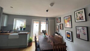 A modern kitchen with a dining area, featuring a wooden table, chairs, and a ceiling light. - Spacious & Central 2BD House - Brighton (Brighton)