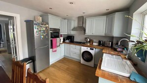 A compact kitchen with a washing machine, a refrigerator, and a stove. - Spacious & Central 2BD House - Brighton (Brighton)