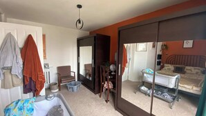 A room with a bed, a chair, a small table, a mirror, and a wardrobe. - Spacious & Central 2BD House - Brighton (Brighton)