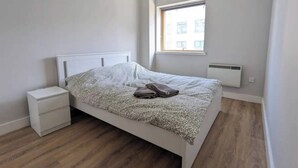 Un dormitorio con una cama, una mesita de noche, una ventana y un radiador.