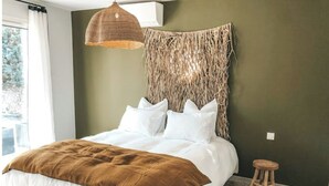 A bedroom with a bed, a hanging light fixture, a stool, and a view of the outdoors. - Villa La Nîmoise (Nîmes)