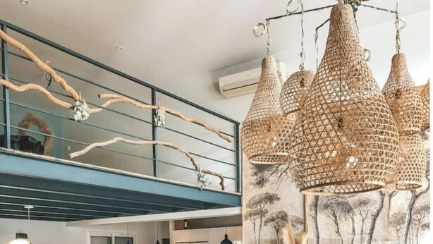 A modern living room with a white sofa, a coffee table, and a dining area with a bar. - Villa La Nîmoise (Nîmes)