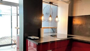 A modern kitchen with a stainless steel countertop, red cabinetry, and pendant lights. - Home for family or business stays (Cambrai)