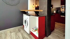 A compact kitchen with a washing machine, a wooden countertop, and hanging pendant lights. - Home for family or business stays (Cambrai)