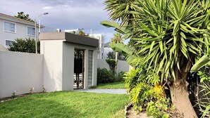 A well-maintained grassy lawn with a small tree and a building with a black gate.