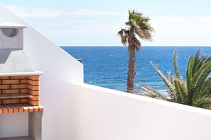 Un balcone con vista sul mare e una palma.