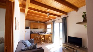 Ein gemütliches Wohnzimmer mit Sofa, Fernseher und einer Küche im Hintergrund.