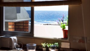 Ein Fenster mit Meerblick, ein Blumentopf und ein Tisch mit einem Glas und einer Tasse.