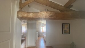 A hallway with wooden beams, a stone wall, and a framed picture.