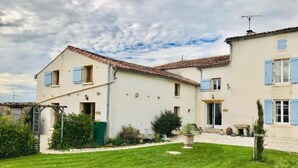 A two-story house with a tiled roof, a well-maintained lawn, and a small garden area with plants and a birdbath.