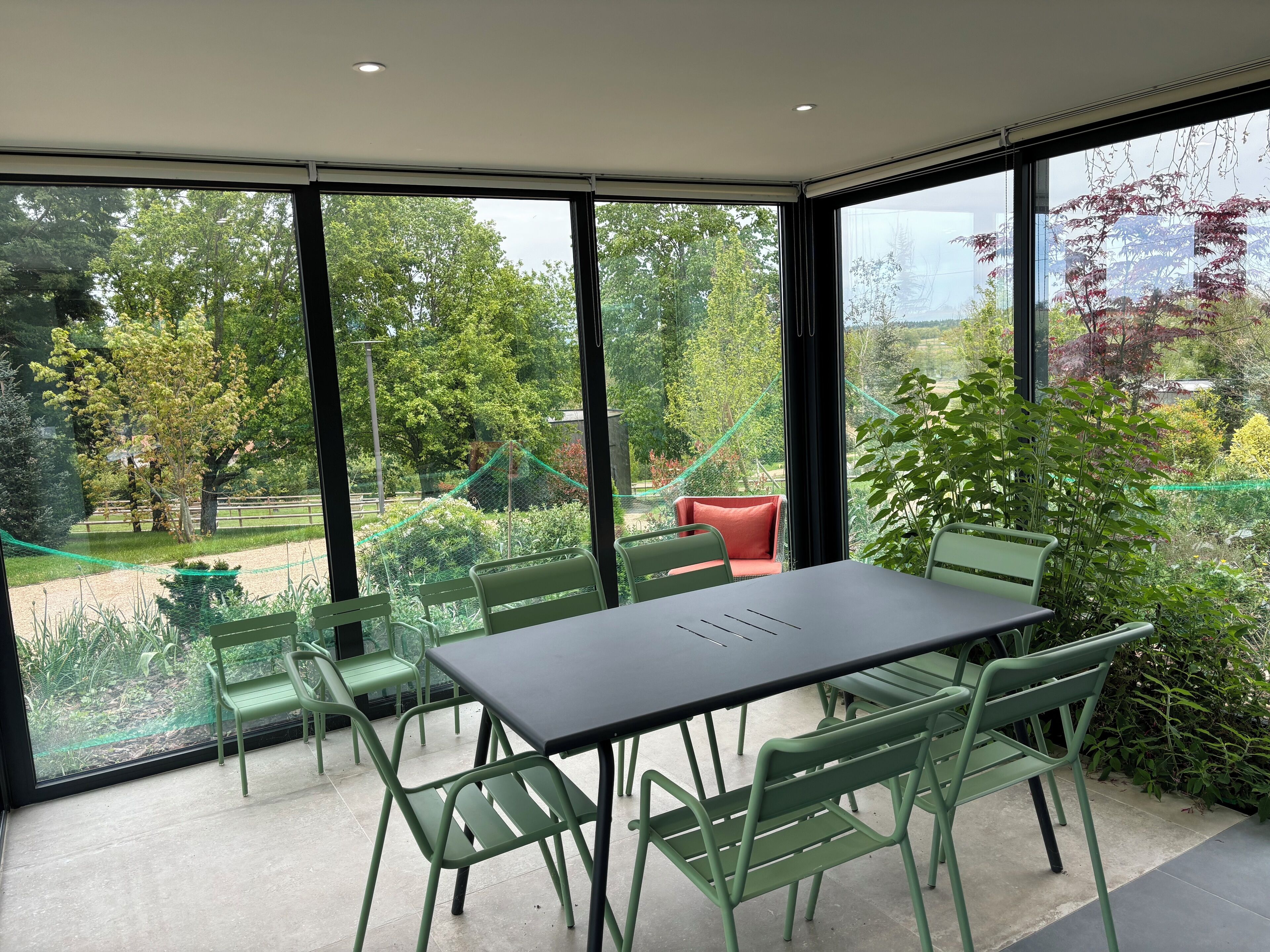 A modern room with a large window, a table, and green chairs.
