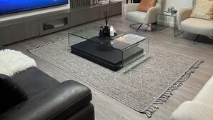 Ein modernes Wohnzimmer mit großem Flachbildfernseher, einem Glastisch und bequemen Sitzmöglichkeiten.