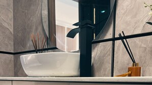 Ein modernes Badezimmer mit einem weißen Waschtisch, einem runden Spiegel und einem integrierten Waschbecken.