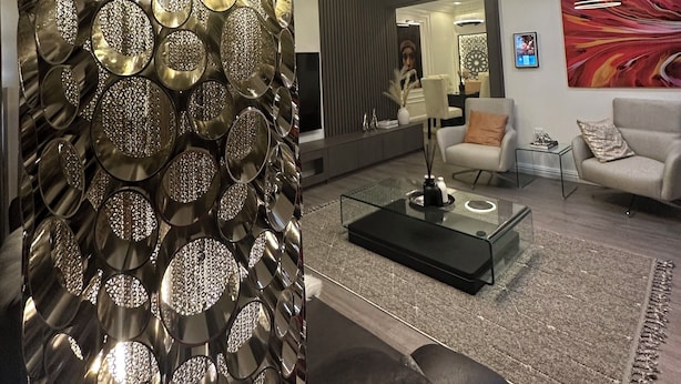 Ein modernes Wohnzimmer mit einer dekorativen Metallwand, einer Decke mit farbenfrohem abstraktem Design, einem großen abstrakten Gemälde und einer Sitzecke mit Couchtisch.