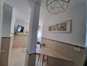 Modern kitchen with sink, wall-mounted TV, and geometric light fixture.