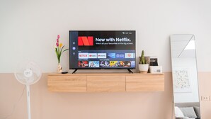 Ett modernt vardagsrum med en TV som är monterad på väggen och visar Netflix.