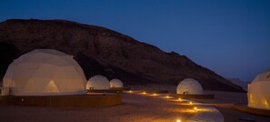 Paesaggio desertico con diverse strutture a forma di cupola, probabilmente utilizzate per osservazioni astronomiche, con vista chiara del terreno roccioso circostante.
