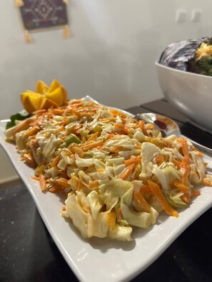 Un piatto di insalata di cavolo cappuccio e carote, guarnito con un fiore giallo.