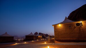 Een woestijnresort met jurten en een groot gebouw met een trap naar een balkon.