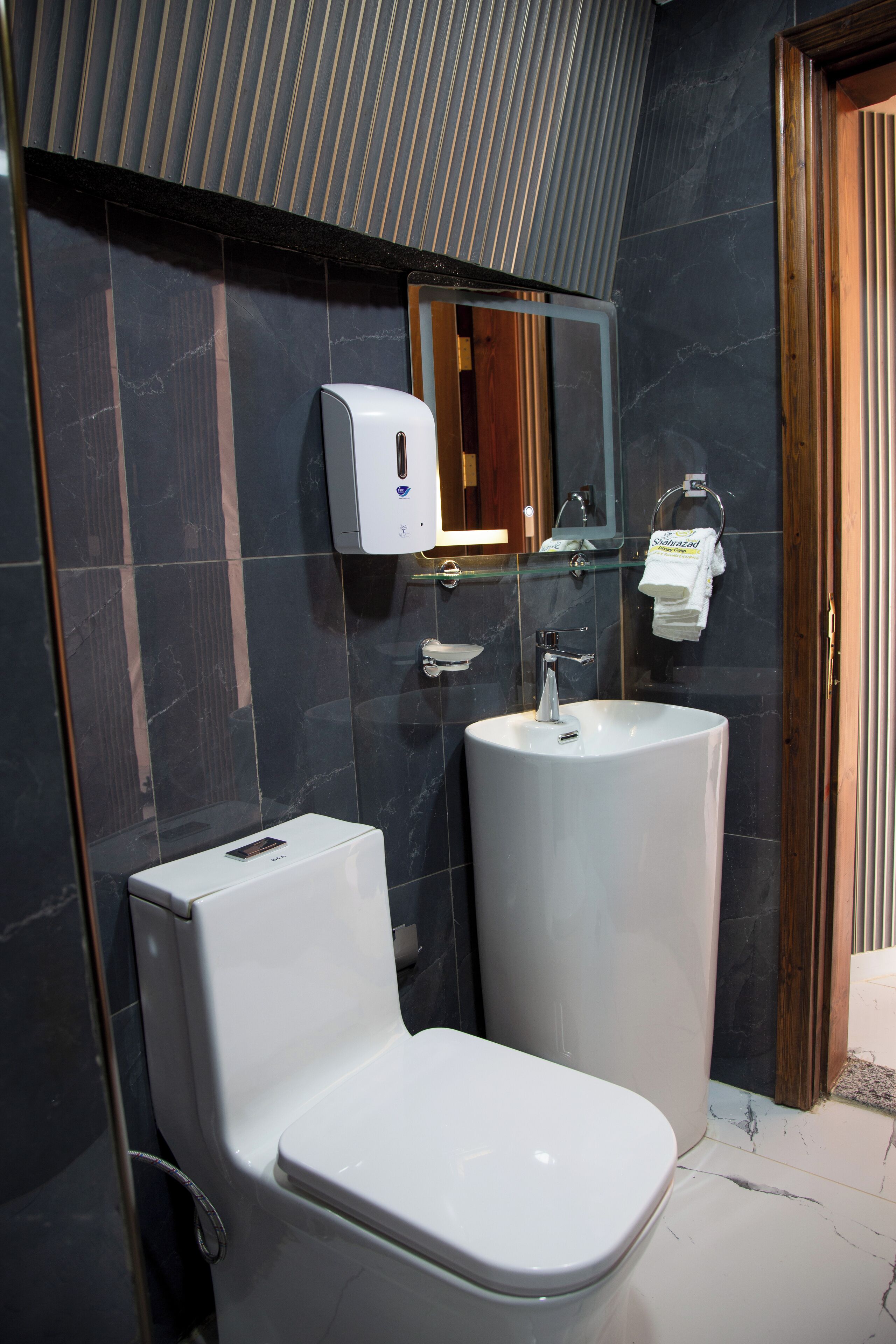 A modern bathroom with a toilet, sink, and hand dryer.