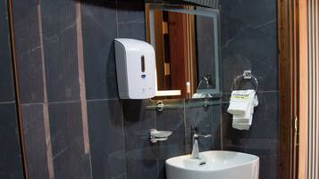 A modern bathroom with a toilet, sink, and hand dryer.