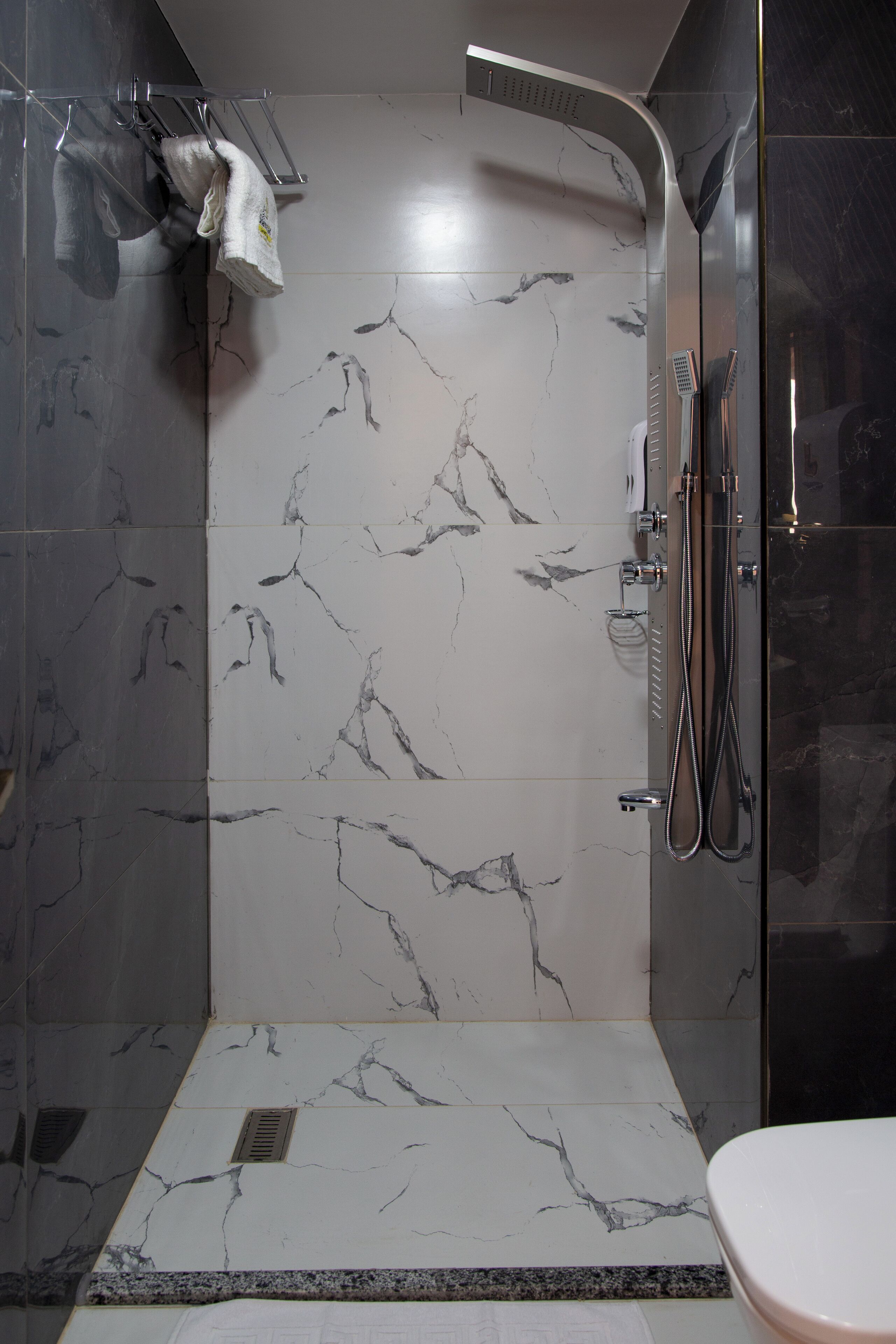 A modern bathroom with a shower, marble tiles, and a toilet.